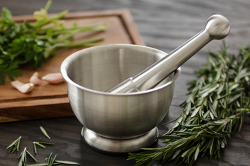 metal mortar pestle on counter with herbs - obrazy, fototapety, plakaty