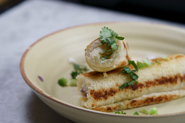 A stack of  toasted bread filled with a mixture of cheese, onion, peppers and cilantro on a plate.