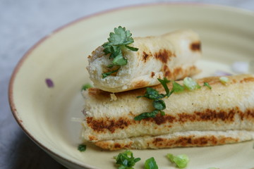 A stack of  toasted bread filled with a mixture of cheese, onion, peppers and cilantro on a plate.