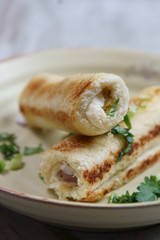 A stack of  toasted bread filled with a mixture of cheese, onion, peppers and cilantro on a plate.