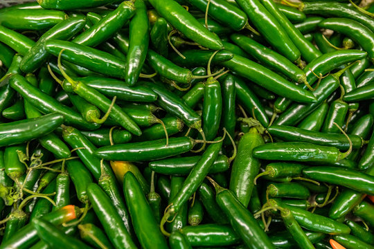 Full frame close up of a bunch of bright and shiny green chili peppers. For wallpaper or background use. Organic vegetables at the local food market.