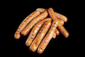 Grilled sausages isolated on black background. Delicious barbecue fast food.