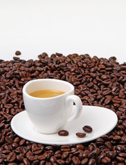 Cup of black coffee on coffee beans background. Hot aromatic americano or espresso cup on saucer.