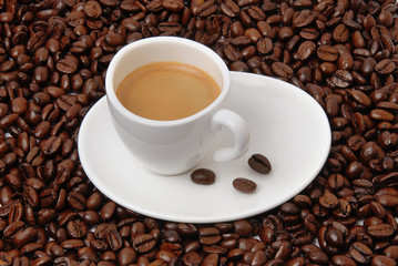 Obraz premium Cup of black coffee on coffee beans background. Hot aromatic americano or espresso cup on saucer.