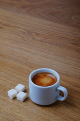Cup of black coffee with sugar on wooden table with copy space. Espresso vertical background.
