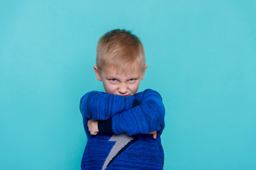 Angry little boy showing frustration and disagreement, isolated on blue background