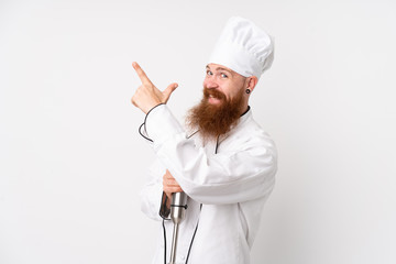 Redhead man using hand blender over isolated white background pointing with the index finger a great idea