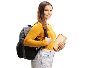 Smiling female student carrying a backpack and holding books