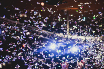 Colourful confetti explosion fired on dance floor air during a concert festival, crowded concert...