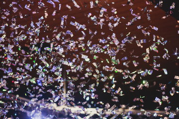 Colourful confetti explosion fired on dance floor air during a concert festival, crowded concert hall with scene stage lights, rock show performance, with people silhouette