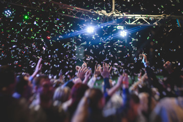 Colourful confetti explosion fired on dance floor air during a concert festival, crowded concert...