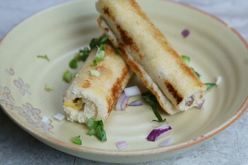 A stack of  toasted bread filled with a mixture of cheese, onion, peppers and cilantro on a plate.
