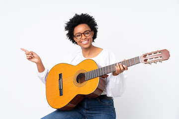 Obraz premium African american woman with guitar over isolated background surprised and pointing finger to the side
