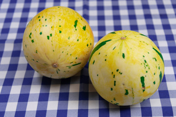 Whole melon fruits on a table on a blue and white tablecloth