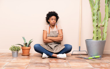 Gardener woman sitting on the floor making doubts gesture while lifting the shoulders