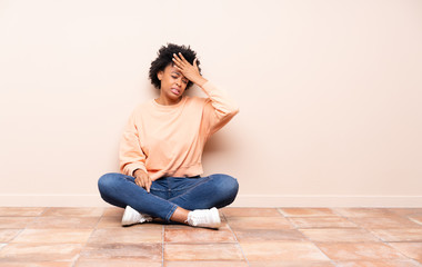 African american woman sitting on the floor with tired and sick expression