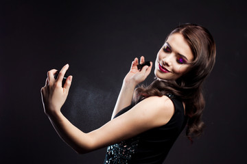 Attractive young brunette woman and a bottle with a new fragrance, use perfume.