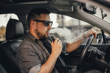 Young handsome man smoke with vape in vehicle