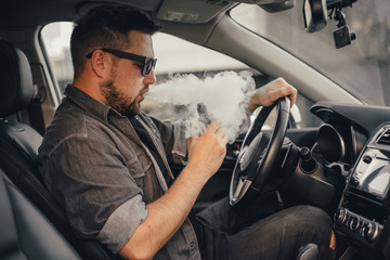Young handsome man smoke with vape in vehicle