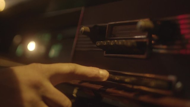 Close-up of man's hand turning on a vintage car radio in retro automobile. Vintage car interior of old automobile