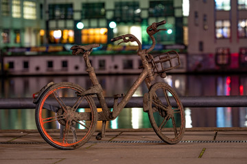 dirty bike at night, with colored blurry background and reflections in the water