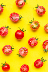 Fresh cherry tomatoes, whole and half cut isolated on yellow background.