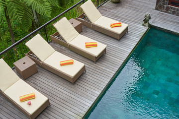 Chaises with towels and tropic coctail in glass near pool at Bali resort  with no people