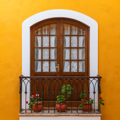 Balcony in the city center of Sucre city decorated with flowers and a yellow colonial style facade,...