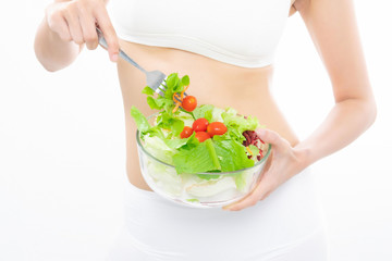 Girl in a white sport bra holds a salad bowl.