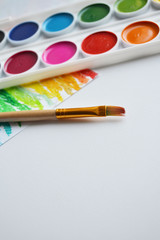 Naklejka premium multicolored paints and brushes lie together on a white background