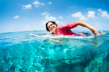 Happy surfer paddles in the ocean