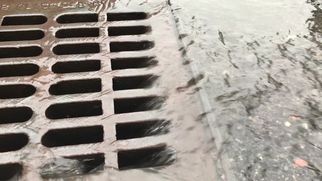 Closeup Of Rain Water Flowing Down The Drain, NYC Street.