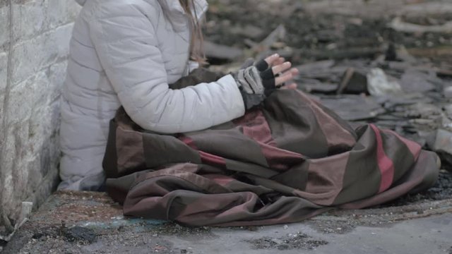 Homeless person in abandoned derelict building trying to keep warm close up