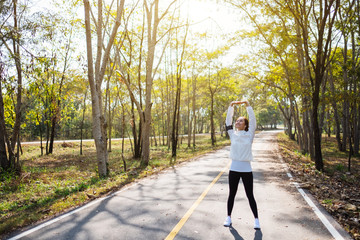 A young asian woman do stretching arms before running in city park