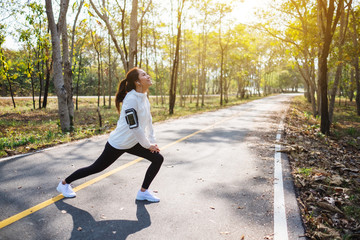 A young asian woman do stretching legs before running in city park