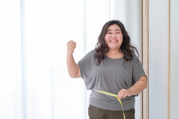 Asian obese women are happy because of size reduction after checking with tape measure. - 323166256