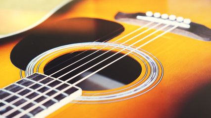 Close-up acoustic guitar on white wall background, vintage filter.