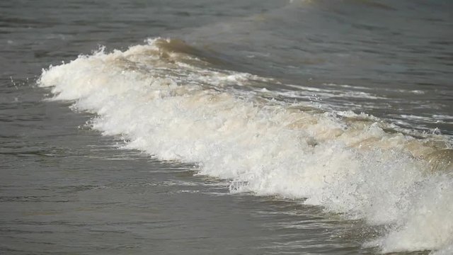 Close up of wave rushing up the muddy beach, high speed camera, super slow motion, 180 FPS, b roll shot.