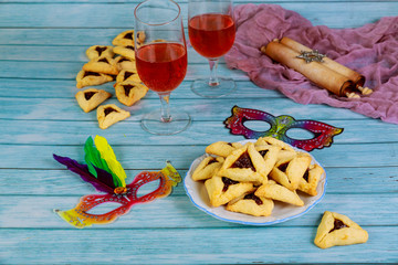Hamantashen cookies, mask, wine and megillah papyrus roll.