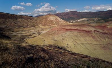 Breathing and colorful Painted Hills covered in red, tan, black, orange, and yellow stripes on a partly cloudy autumn day at the John Day Fossil Beds in Mitchell Oregon