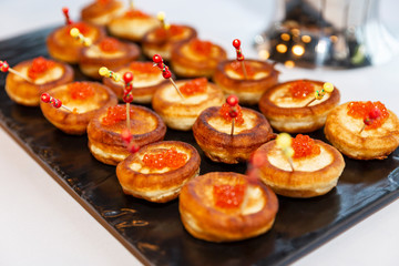 Appetizing snacks on the buffet table at the event. Canapes with red caviar. Close-up.