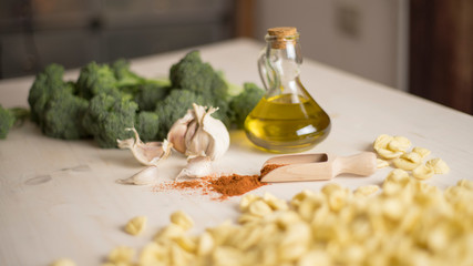 Close-up of typical Italian Apulian fresh pasta orecchiette on a table with broccoli, garlic, oil and chilli powder 