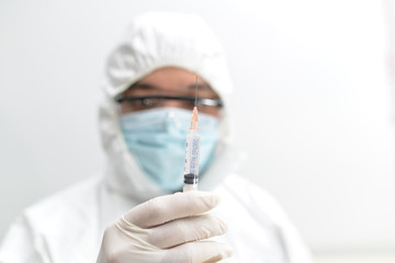 Asian male doctor wearing protective suits holding a new vaccine Coronavirus (nCoV, Covid-19) in International standard biological laboratory. New testing for coronavirus emerges.