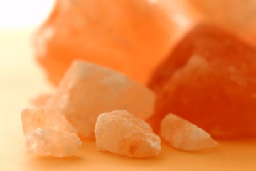 Pink Himalayan salt  pieces set on a light orange blurred background. Saindhava lavana or Himalayan .Pink rock salt.Pink salt minerals in rock from Himalaya