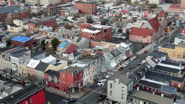 City housing, urban street corner establishing shot, intersection, tight aerial drone shot tilting up to reveal downtown business district and skyscraper office buildings in Reading, Pennsylvania, USA