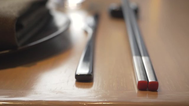Fancy silverware and chopstick in an Asian restaurant on the table next to the plate during lunch time break
