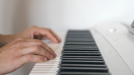 The young man plays a piano. Close up oh his hands