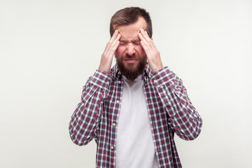 Headache. Portrait of unhealthy tired bearded man in casual plaid shirt massaging head to relieve...