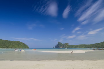 Fototapeta na wymiar view seaside of speed boats, white sand beach and mountains with clouds moving in blue sky background, loh dalum beach, Phi Phi Don island, Krabi, southern of Thailand.