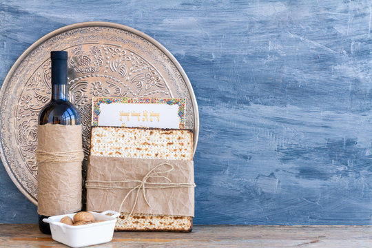 Metal plate with matzah or matza and Passover Haggadah on a vintage wood background presented as a Passover seder feast or meal with copy space. Translation: Passover Haggadah